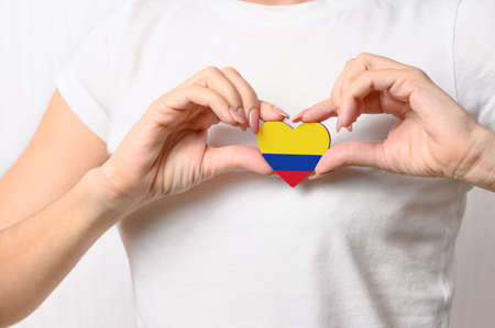 Love Colombia. The girl holds a heart in the form of the flag of Colombia on her chest. Colombian patriotism conceptの写真素材