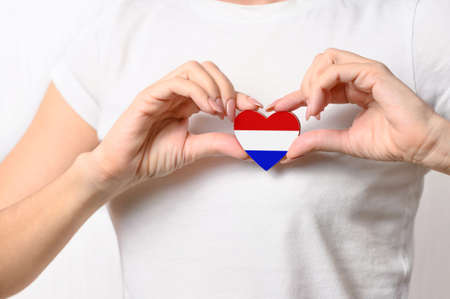 Love Netherlands. The girl holds a heart in the form of the flag of the Netherlands on her chest. Dutch patriotism conceptの写真素材