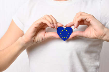 Love European Union. The girl holds a heart in the form of the flag of EU on her chest. European patriotism conceptの写真素材