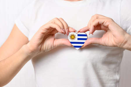 Love Uruguay. The girl holds a heart in the form of the flag of Uruguay on her chest. Uruguayan patriotism conceptの写真素材