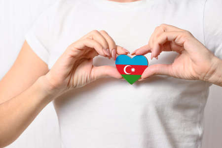 Love Azerbaijan. The girl holds a heart in the form of the flag of Azerbaijan on her chest. Azerbaijani patriotism conceptの写真素材