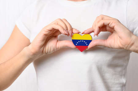 Love Venezuela. The girl holds a heart in the form of the flag of Venezuela on her chest. Venezuelan patriotism conceptの写真素材