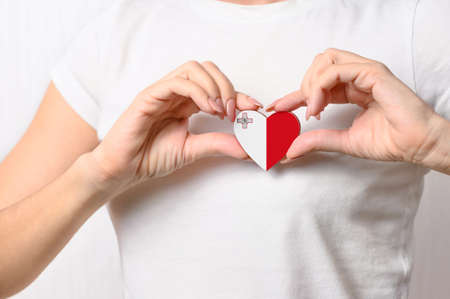 Love Malta. The girl holds a heart in the form of the flag of Malta on her chest. Maltese concept of patriotismの写真素材