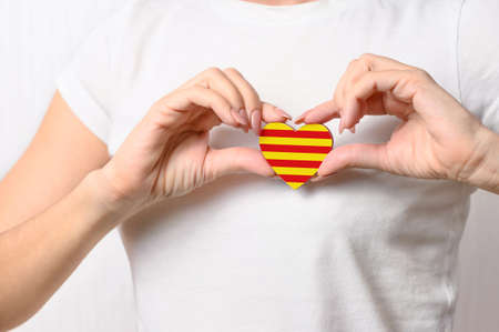 Love Catalonia. The girl holds on her chest a heart in the form of the official flag of Catalonia. Catalan patriotism concept.の写真素材