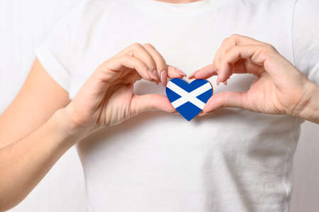 Love Scotland. The girl holds a heart in the form of the flag of Scotland on her chest. Scottish patriotism conceptの写真素材