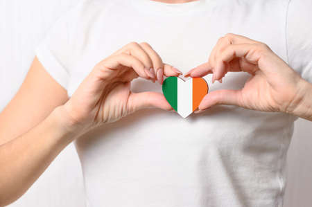 Love Ireland. The girl holds a heart in the form of the flag of Ireland on her chest. Irish patriotism conceptの写真素材