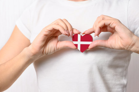 Love Denmark. The girl holds a heart in the form of the flag of Denmark on her chest. Danish concept of patriotism;の写真素材