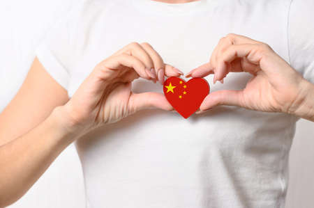 Love China. A girl holds a heart in the form of a flag of China on her chest. Chinese patriotism conceptの写真素材