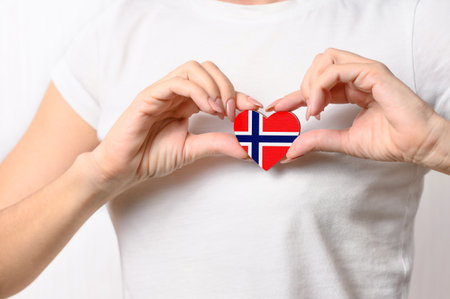Love Norway. The girl holds a heart in the form of the flag of Norway on her chest. Norwegian patriotism conceptの写真素材