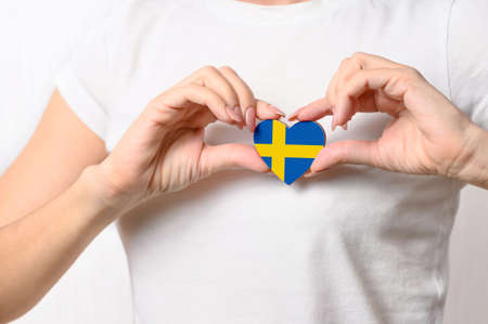 Love Sweden. The girl holds a heart in the form of the flag of Sweden on her chest. Swedish patriotism conceptの写真素材