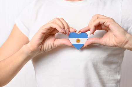 Love Argentina. The girl holds a heart in the form of the flag of Argentina on her chest. Argentine patriotism conceptの写真素材