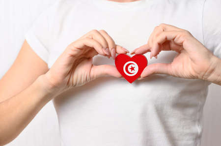 Love Tunisia. The girl holds a heart in the form of the flag of Tunisia on her chest. Tunisian concept of patriotismの写真素材