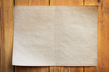 An old sheet of squared paper lies on an old wooden table. Blank sheet of paper.の写真素材
