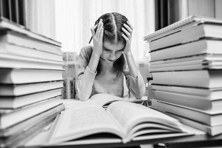 Black and white portrait of a sad girl during home schooling. The girl is upset by a difficult...