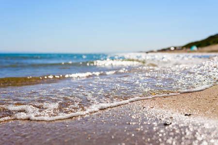 Sandy coast of the Black Sea. Background on the marine theme. Focusing on the water's edge. Shallow depth of field and blurred foreground and background.の写真素材