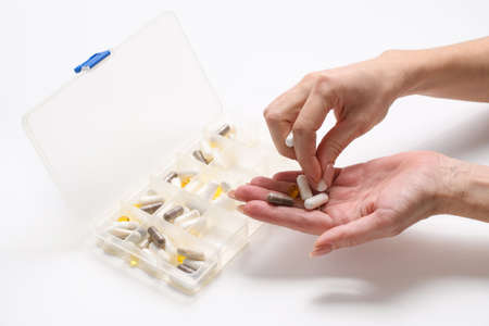Female hands take pills from a plastic box. The concept of daily medication or vitamin intake.の写真素材
