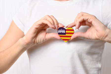 Flag of Balearic Islands in the shape of a heart in the hands of a girl. Love Mallorca. The concept of patriotism and tourismの写真素材