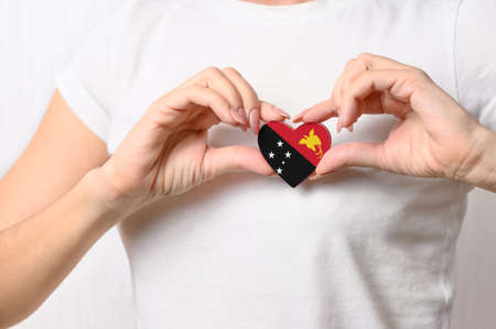 Flag of Papua New Guinea in the shape of a heart in the hands of a girl. Love Papua New Guinea. The concept of patriotism and tourismの写真素材
