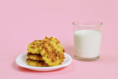 Healthy breakfast. Homemade homemade peanut cookie lies on a white plate. A glass of milk stands next to a pink background.の写真素材