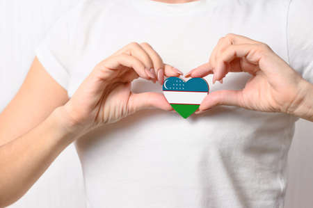 Flag of Uzbekistan in the shape of a heart in the hands of a girl. Love Uzbekistan. The concept of patriotism for Uzbeksの写真素材