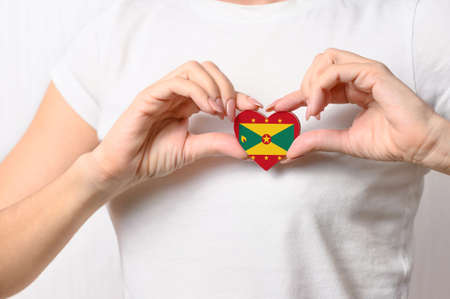 Grenada flag in the shape of a heart in the hands of a girl. Love Grenada. Grenada patriotism and tourism conceptの写真素材