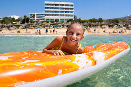 Joyful girl in the sea on an inflatable mattress on the background of the shore. The girl is swimming in the sea.の写真素材