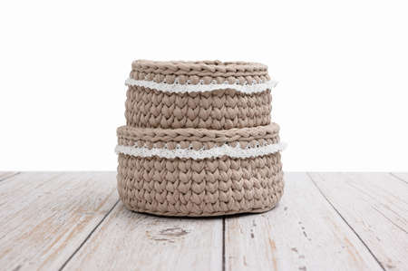 Two empty knitted beige baskets stand in the form of a tower on a table on a white background. Isolated background.の写真素材