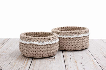 Knitted baskets stand on a wooden table on a white background. Selective focusing on the near basket. Isolated background for possible replacement ..の写真素材