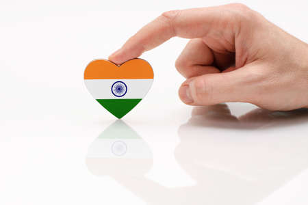 Love and respect India. A man's hand holds a heart in the shape of the Indian flag on a white glass surface. The concept of Indian patriotism and pride.の写真素材