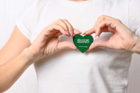 Flag of Saudi Arabia in the shape of a heart in the hands of a girl. Love Saudi Arabia. The concept of patriotism for Iraniansの写真素材