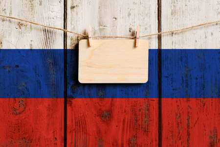 Wooden plaque with empty space for text hangs against the background of the old flag of Russia.の写真素材