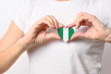 Flag of Nigeria in the shape of a heart in the hands of a girl. Love Nigeria. Respect for the people of Nigeriaの写真素材
