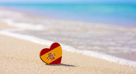 Flag of Spain in the shape of a heart on a sandy beach. The concept of the best vacation in Spainの写真素材