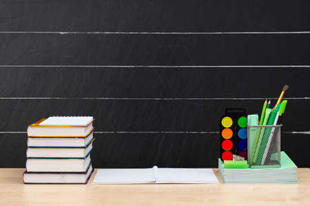 A stack of textbooks and office supplies on the table against the background of the school board....
