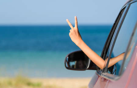 Positive hand gesture from the car window on the background of the sea and the beach. The concept of...