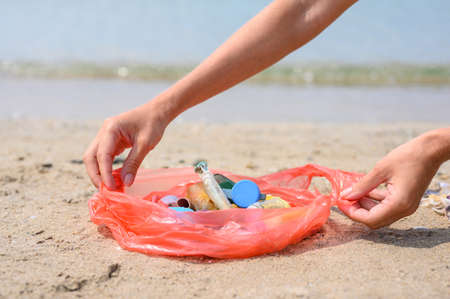 Small garbage collected on the beach left by tourists. The girl holds a package with garbage on the...