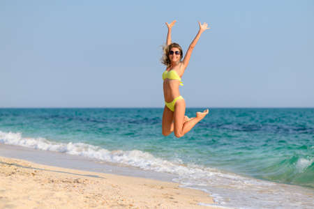 Happy slender girl jumping on the seashore. The concept of a great seaside vacation.の写真素材