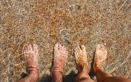 Male and female feet underwater on the seashore. A couple in love on a sea vacation. View from above.の写真素材