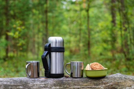 A picnic in the woods on a strom log two mugs and cookies on a log. Horizontal format.の写真素材