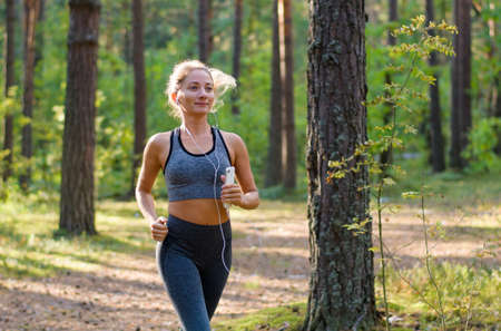 Girl jogging in a pine forest, Girl running and listening to musicの写真素材