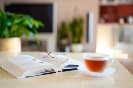 Reading people on vacation. A book with glasses and a cup of herbal tea. Selective focus on glassesの写真素材