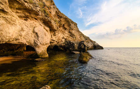 Seascape at sunset. Rocky coast with caves from sea waves.の写真素材