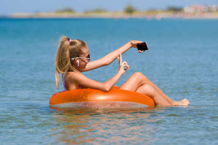Joyful at a seaside resort, taking a selfie or chatting. Girl swims in the seaの写真素材