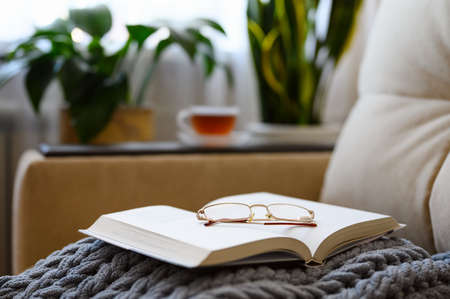 Open book with glasses on a woolen blanket. Selective focus on glasses.の写真素材