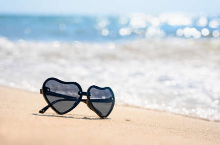 Sunglasses on the beach near the sea waves. Selective focus, narrow focus.の写真素材