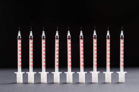 Many insulin syringes stand flat against a black background.の写真素材