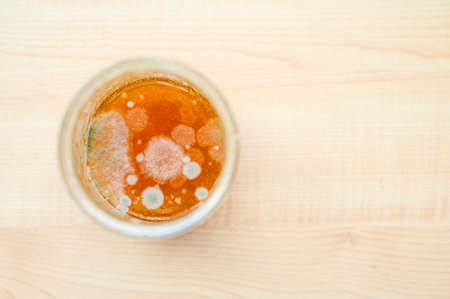 Jar of moldy jam on a wooden background. Selective focus on mold.の写真素材