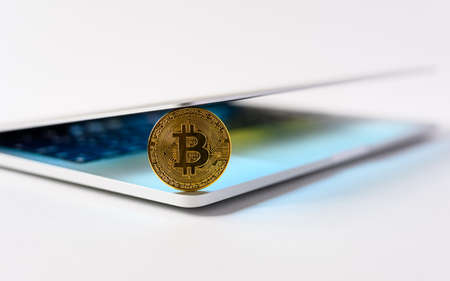 Bitcoin coin stands on a laptop on a light background.の写真素材