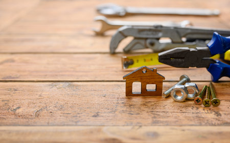 Wooden house and construction tools. House construction concept. Selective focus on a small house, empty space on the left.の写真素材