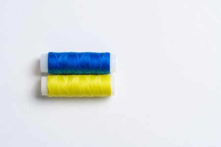 Two spools of thread for sewing are stacked in the form of the flag of Ukraine on a white background. Concept of Ukrainian patriotism and the country's garment industry. There is a free empty space.の写真素材